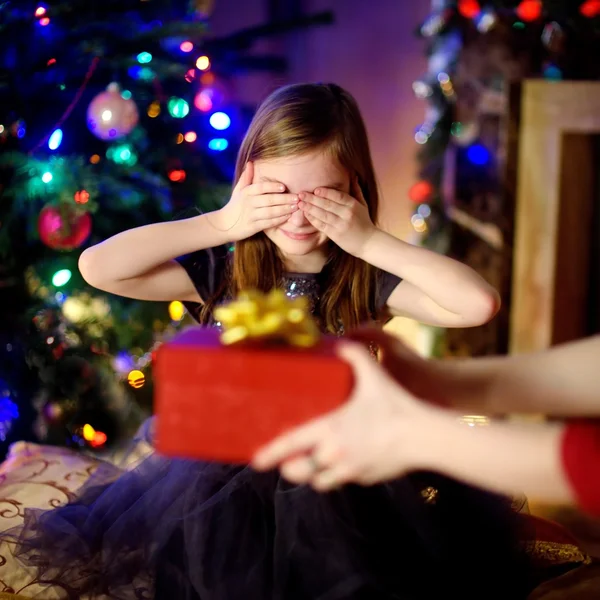 Щаслива маленька дівчинка отримує різдвяний подарунок від своєї мами — стокове фото