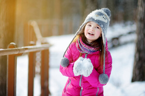 Забавная маленькая девочка развлекается в зимнем парке
