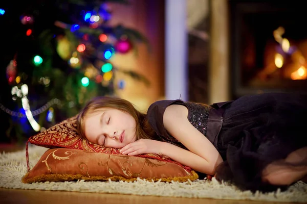Adorable petite fille dormant sous le sapin de Noël près d'une cheminée — Photo