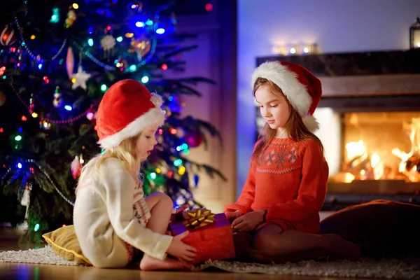 Hermanas abriendo regalo mágico de Navidad junto a una chimenea —  Fotos de Stock