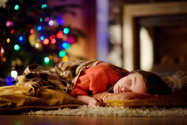 Urocza dziewczynka spanie pod choinkę przy kominku — Zdjęcie stockowe