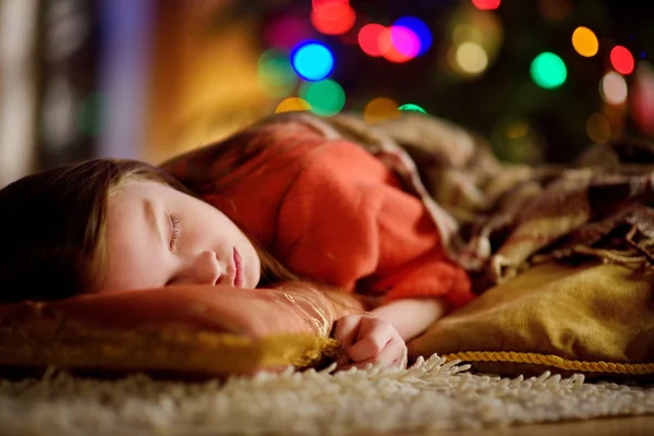 壁炉旁的圣诞树下睡觉的可爱小女孩 — 图库照片