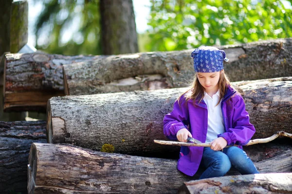 Linda niña usando una navaja para blanquear un palo — Foto de Stock