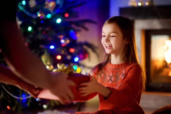 Happy little girl getting a Christmas gift from her parent — Stock Photo, Image