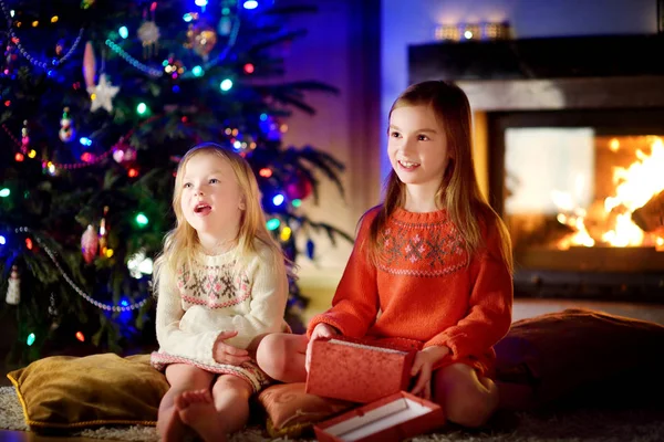 Irmãs abrindo presente mágico de Natal por uma lareira — Fotografia de Stock
