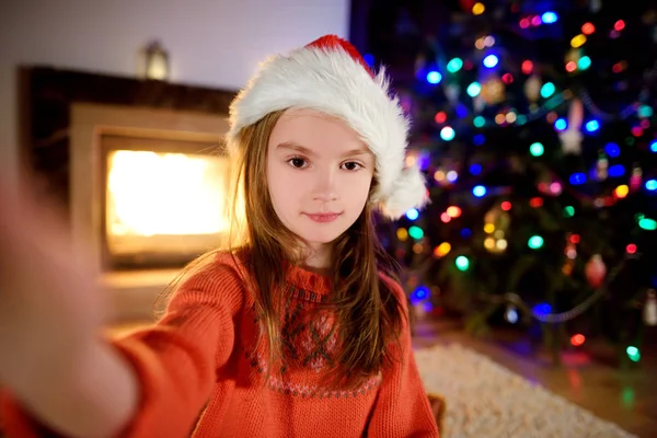 Glückliches kleines Mädchen macht ein Selfie an einem geschmückten Weihnachtsbaum — Stockfoto