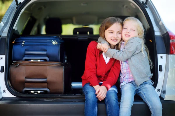 Dvě rozkošné malé sedí v autě před odchodem na prázdniny s rodiči — Stock fotografie