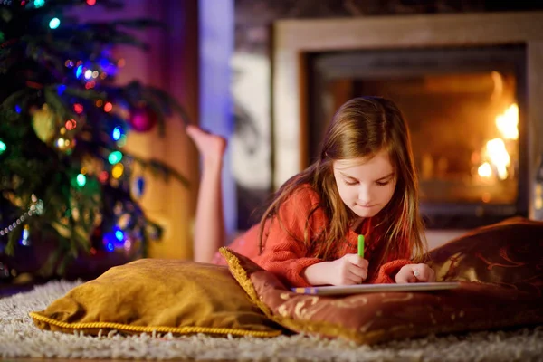 Sevimli küçük kız Noel Baba'ya bir mektup yazma — Stok fotoğraf