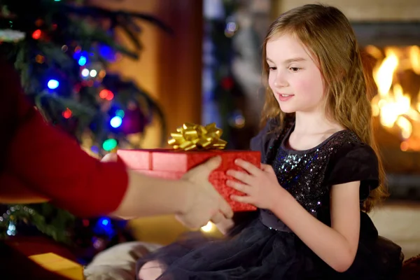 Glückliches kleines Mädchen bekommt ein Weihnachtsgeschenk von ihren Eltern — Stockfoto