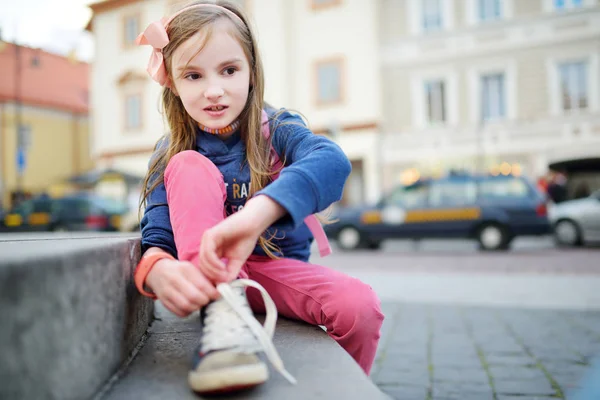 Девушка учится завязывать шнурки на улице — стоковое фото