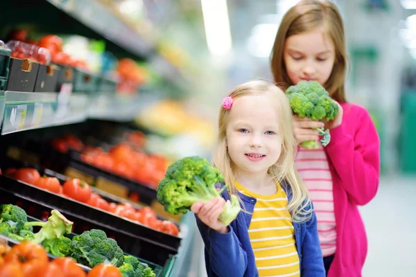 Två små systrar att välja broccoli — Stockfoto