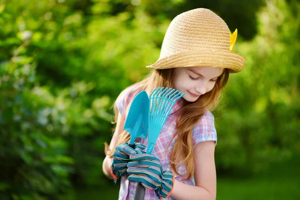 Fille portant chapeau de paille tenant outils de jardin — Photo