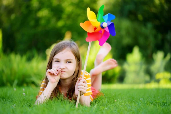 小女孩抱着五彩缤纷的玩具风车 — 图库照片