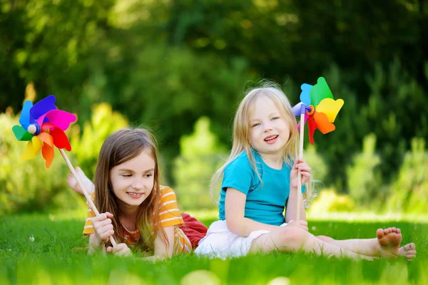 Meninas segurando pinwheels brinquedo colorido — Fotografia de Stock