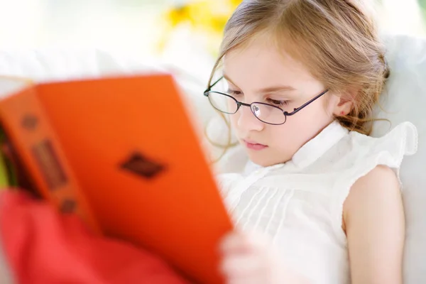 Küçük kız bir kitap okuma gözlük takıyor — Stok fotoğraf