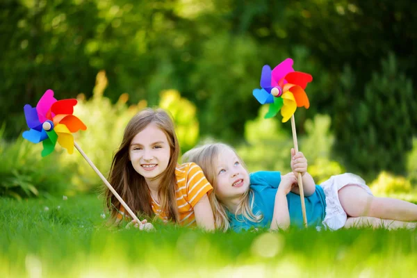 Κοριτσάκια κρατώντας pinwheels πολύχρωμο παιχνίδι — Φωτογραφία Αρχείου
