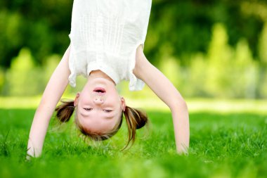 topukların üzerinde yeşil çimenlerin üzerinde oynayan çocuk