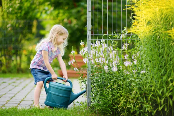 Petite fille arrosant des fleurs dans le jardin — Photo