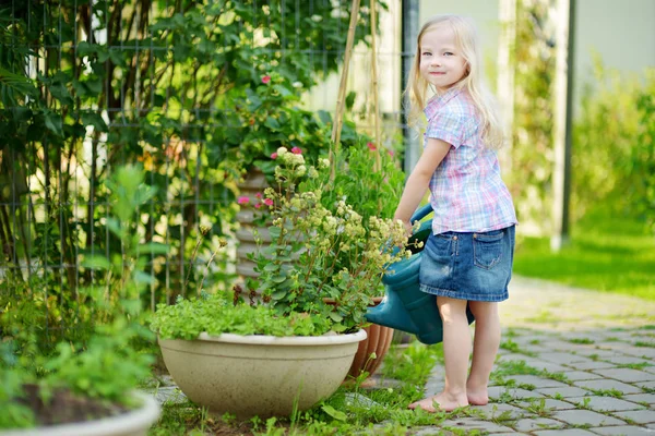Meisje water geven bloemen in de tuin — Stockfoto