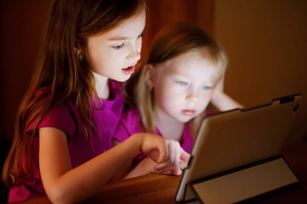 Маленькие сестры играют с цифровым планшетом — стоковое фото