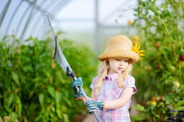 Маленькая девочка в соломенной шляпе с садовым инструментом — стоковое фото