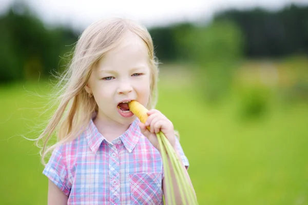 Menina comendo cenoura amarela orgânica fresca — Fotografia de Stock