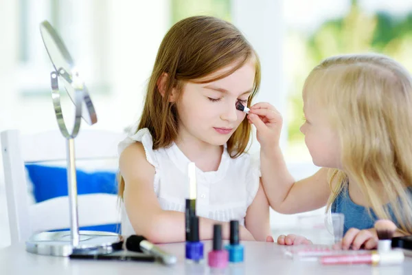 Dos hermanas graciosas lindas aplicando maquillaje — Foto de Stock