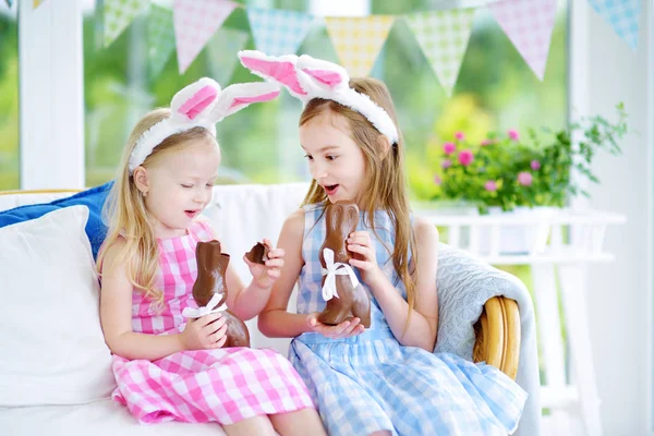 Sisters eating chocolate Easter rabbits — Stock Photo, Image
