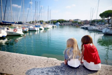 sisters watching small yachts  clipart