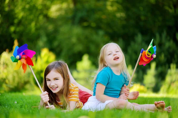 Meisjes houden van kleurrijke speelgoed pinwheels — Stockfoto