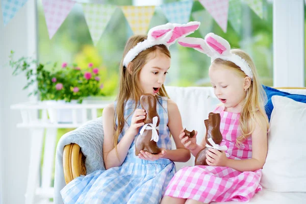 Sisters eating chocolate rabbits — Stock Photo, Image