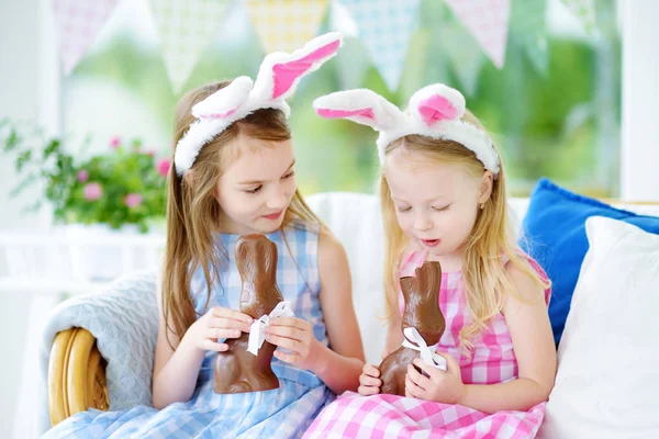 Sisters eating chocolate rabbits — Stock Photo, Image