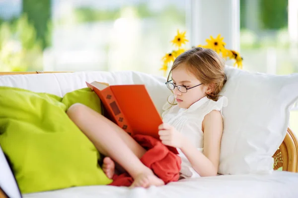 Menina vestindo óculos leitura livro — Fotografia de Stock