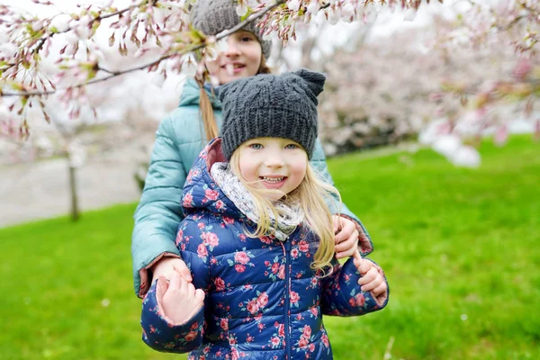 Systrar som har kul i blommande trädgård — Stockfoto