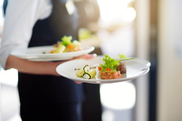 Waiter carrying plates with dishes  