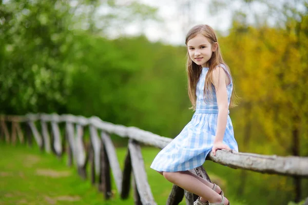 Meisje zittend op houten hek — Stockfoto
