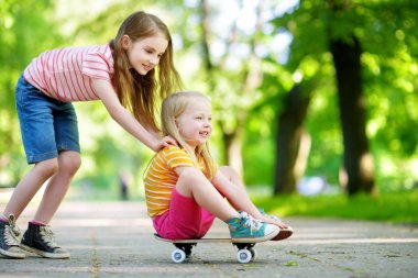 İki sevimli küçük kız kaykay için öğrenme 