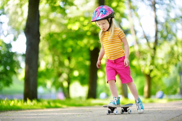 Досить маленька дівчинка вчиться скейтборді — стокове фото