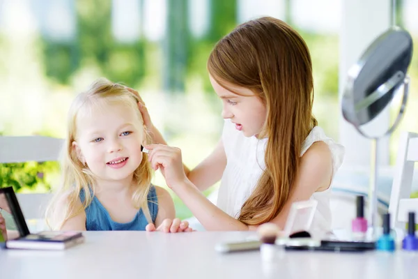 Dos hermanas graciosas lindas aplicando maquillaje — Foto de Stock