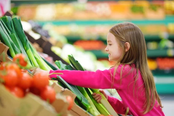 Niña eligiendo puerro fresco — Foto de Stock