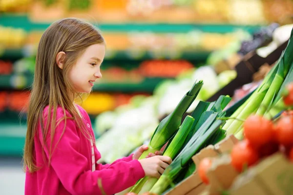 Niña eligiendo puerro fresco — Foto de Stock