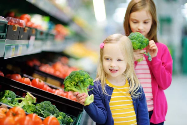 Two cute little sisters in a food store — Stock Photo, Image