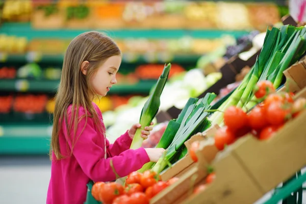 Niña eligiendo puerro fresco — Foto de Stock