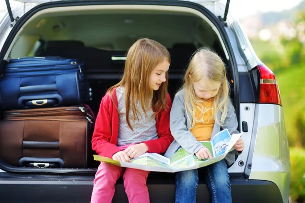 Girls sitting in open trunk of car — Stock Photo, Image