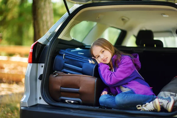 Girl lying on suitcases in trunk of car — Stock Photo, Image