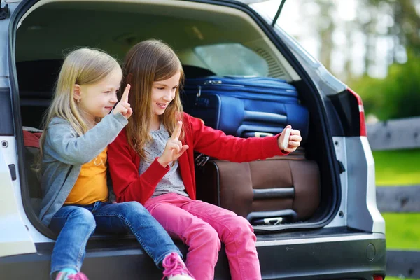 Girls sitting in open trunk of car — Stock Photo, Image