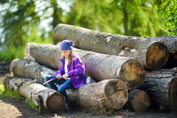 Petite fille assise sur des billes d'arbre — Photo