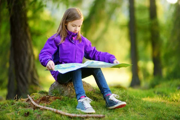 Kleines Mädchen schaut im Wald auf Landkarte — Stockfoto