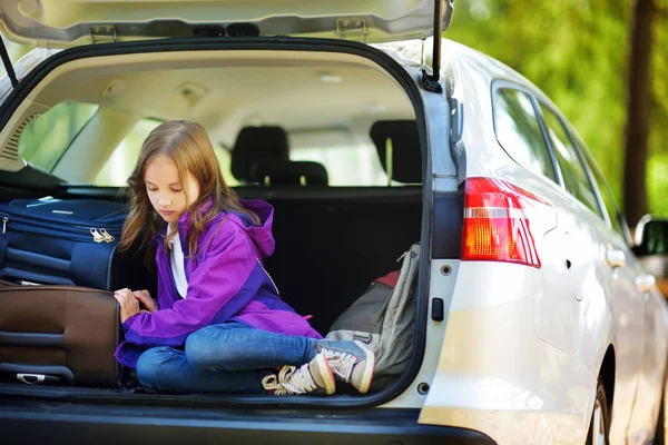 Девушка сидит рядом с чемоданами в багажнике автомобиля — стоковое фото