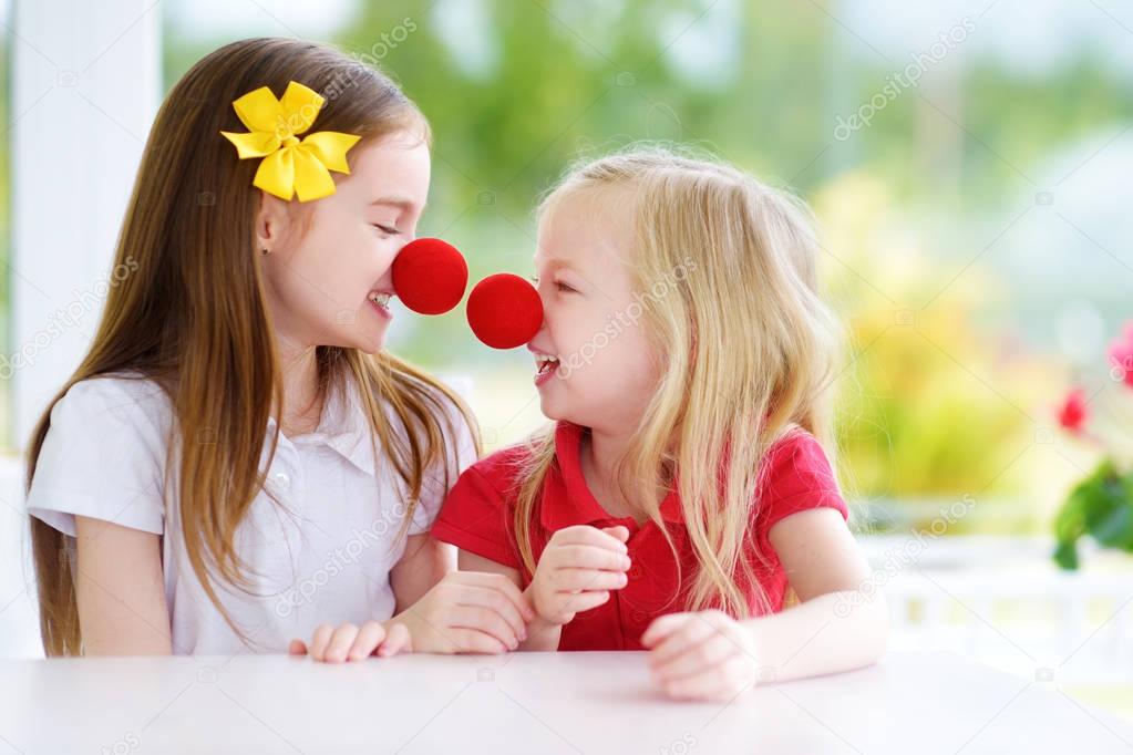 little sisters wearing clown noses